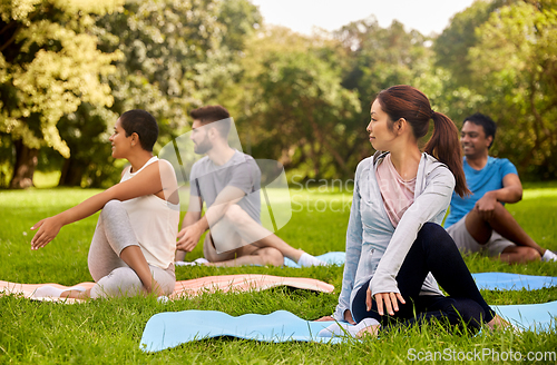 Image of group of people doing yoga at summer park