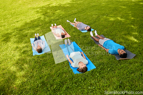 Image of group of people doing yoga at summer park