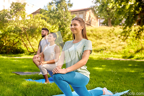 Image of group of people doing yoga at summer park