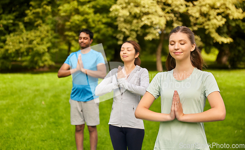 Image of group of people doing yoga at summer park