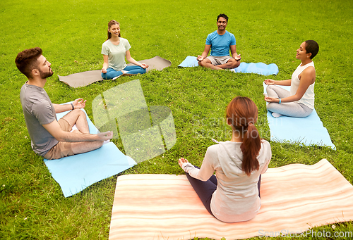 Image of group of people doing yoga at summer park