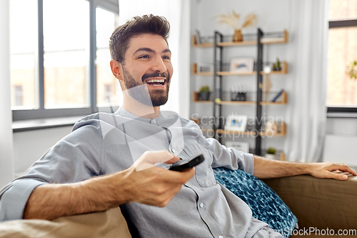 Image of happy man with remote control watching tv at home