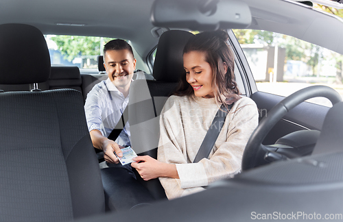 Image of female car driver taking money from passenger