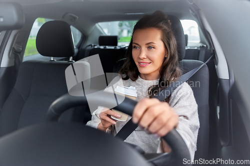 Image of woman or female driver with coffee driving car