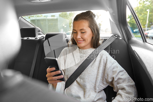 Image of happy smiling woman in car using smartphone