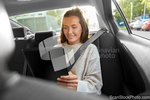 Image of happy smiling woman in car using tablet computer