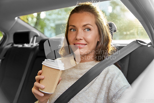 Image of smiling woman or passenger drinking coffee in car