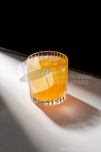 Image of glass of orange juice with ice on table