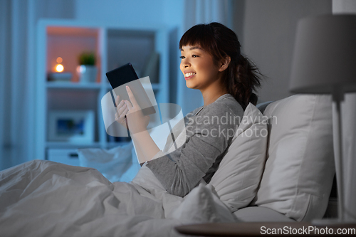 Image of asian woman with tablet pc in bed at home at night