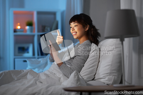 Image of woman with tablet pc in bed has video call at night
