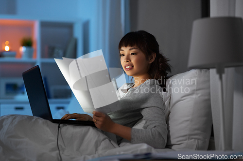 Image of woman with laptop working in bed at night