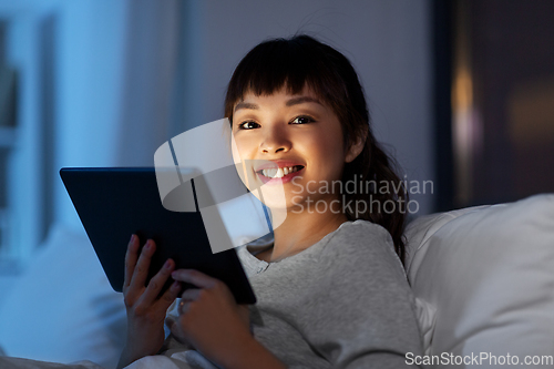 Image of asian woman with tablet pc in bed at home at night