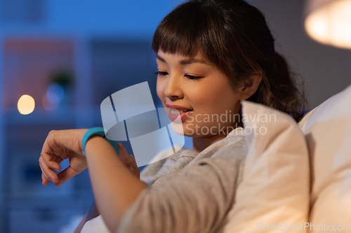 Image of asian woman with health tracker in bed at night