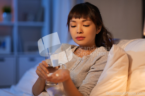 Image of stressed asian woman taking medicine at night