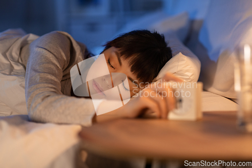 Image of asian woman with clock sleeping in bed at night