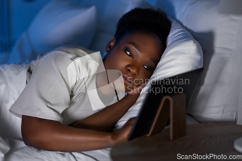 Image of woman with tablet pc in bed at home at night