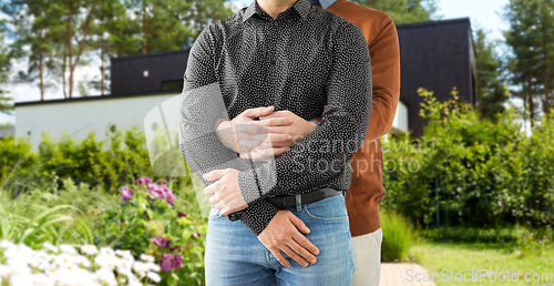 Image of close up of hugging male gay couple at garden