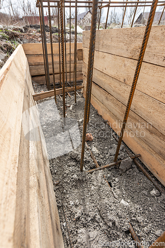 Image of Reinforcement of the strip foundation, the trench is partially covered with earth