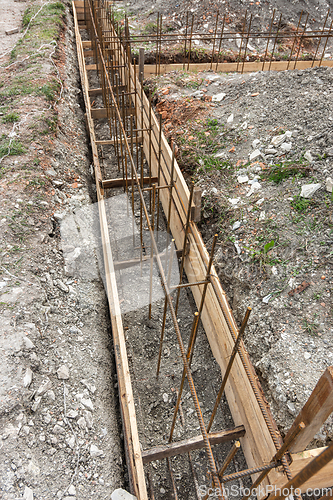Image of Fragment of reinforcement of the strip foundation, the trench is partially covered with earth