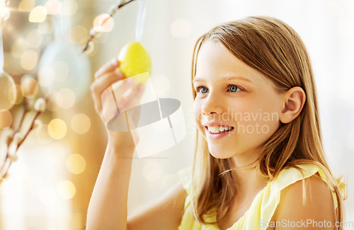 Image of girl decorating willow by easter eggs at home