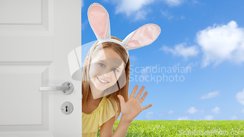 Image of happy girl with easter bunny ears peeking out door