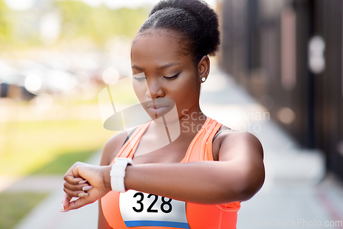 Image of african female marathon runner with smart watch