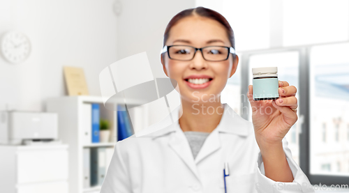 Image of smiling female doctor holding jar of medicine