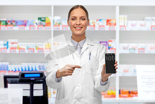 Image of happy female doctor with smartphone at pharmacy