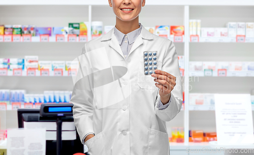 Image of smiling female doctor holding medicine at pharmacy