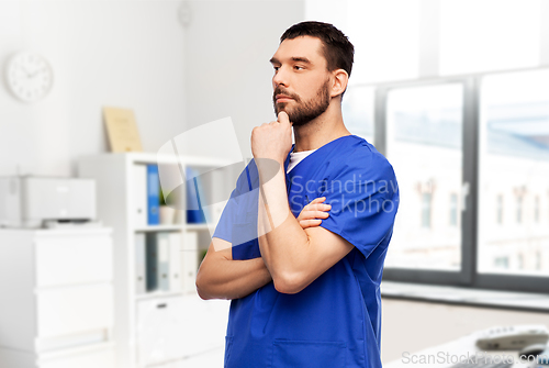 Image of thinking doctor or male nurse in blue uniform