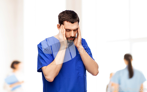 Image of stressed doctor or male nurse in blue uniform