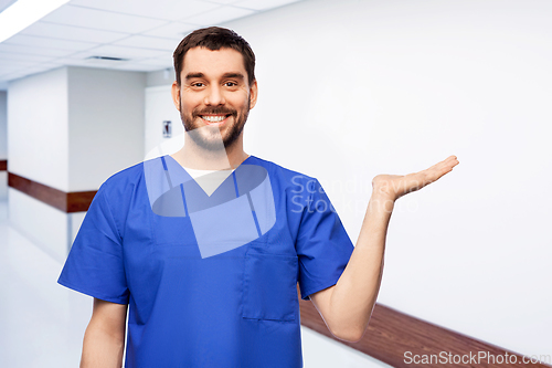 Image of smiling male doctor holding something on hand