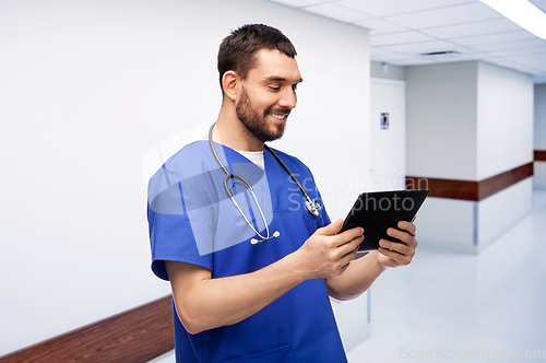 Image of smiling doctor or male nurse using tablet computer