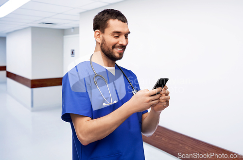 Image of smiling doctor or male nurse using smartphone