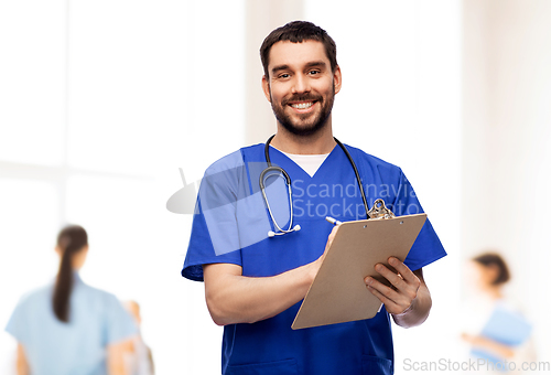 Image of male doctor writing medical report on clipboard