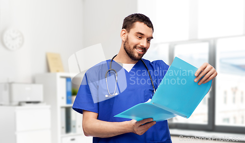 Image of happy male doctor reading medical report in folder