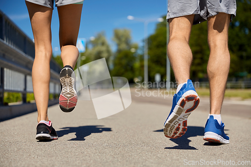 Image of feet of sporty couple running along city road