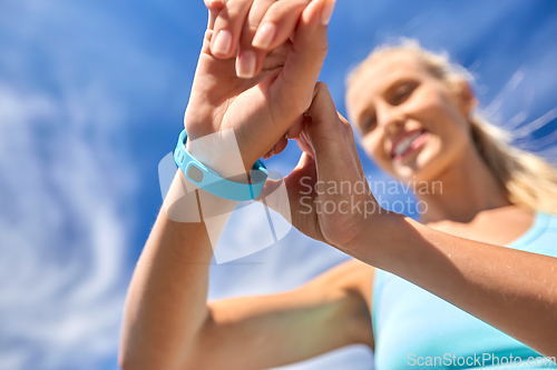 Image of smiling young woman with fitness tracker outdoors