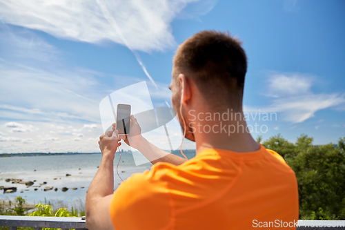 Image of young man with smartphone and earphones outdoors