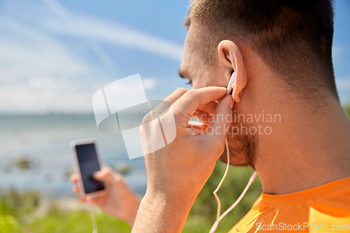 Image of young man with smartphone and earphones outdoors