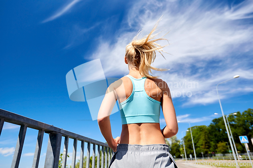 Image of sporty young woman running outdoors