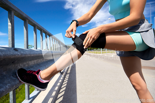 Image of young woman in knee band doing sports outdoors