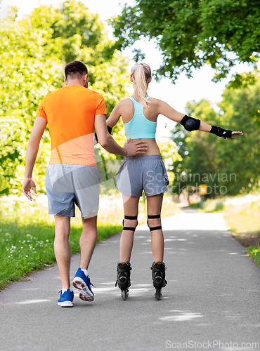 Image of happy couple with roller skates riding outdoors
