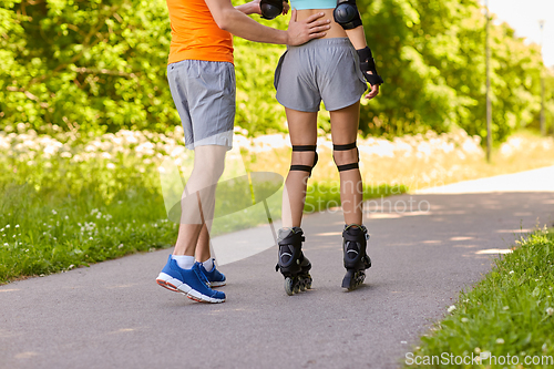 Image of happy couple with roller skates riding outdoors