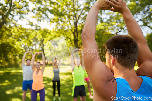 Image of happy people exercising with trainer at park
