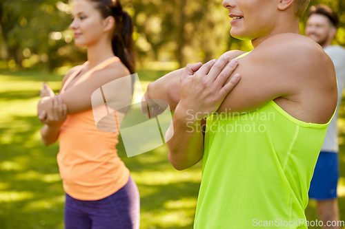 Image of happy people exercising with trainer at park