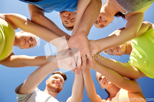 Image of group of happy sporty friends stacking hands