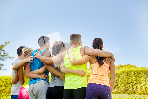 Image of group of happy sporty friends hugging outdoors