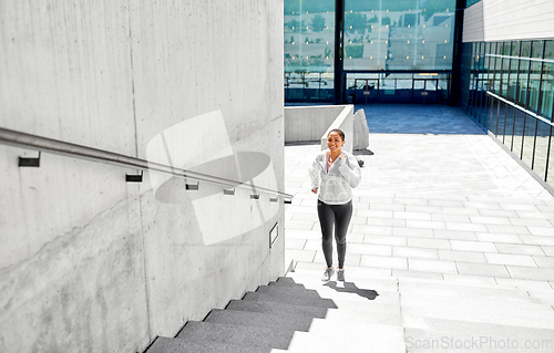 Image of african american woman running upstairs outdoors