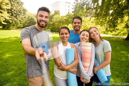 Image of people with yoga mats taking selfie at park